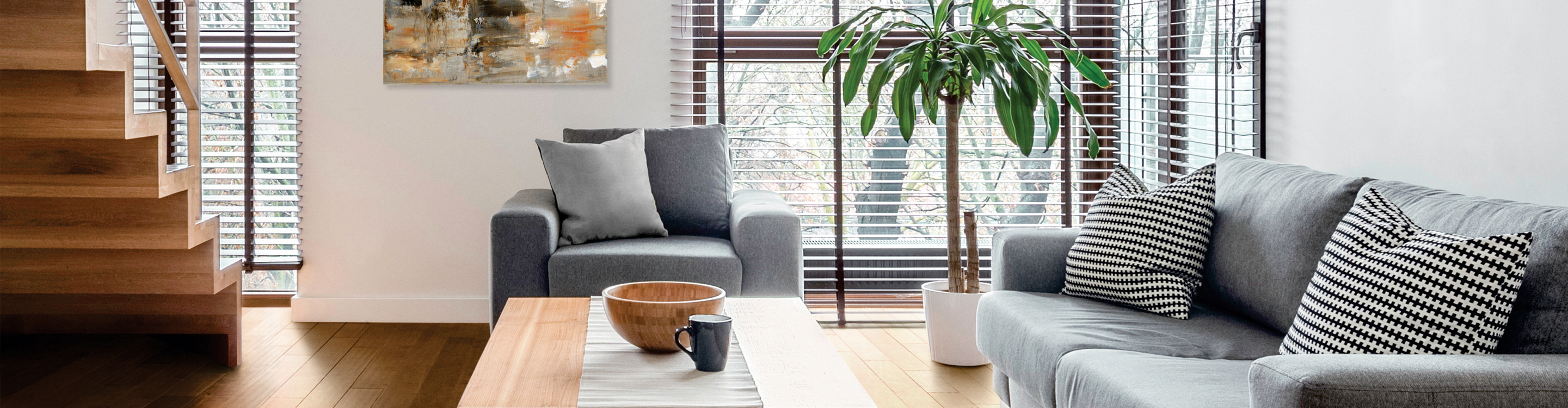 wood look blinds in living area with light wood flooring and gray furniture